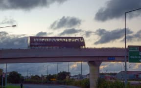 Double decker bus goes on a flyover against a back lit sky in Auckland New Zealand.