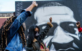 In this file photo taken on October 14, 2020 Paris Stevens (L) and Angela Harrelson (R), George Floyd's cousin and aunt, hold their fists as people gather in celebration of George Floyd's 47th birthday in Minneapoli.