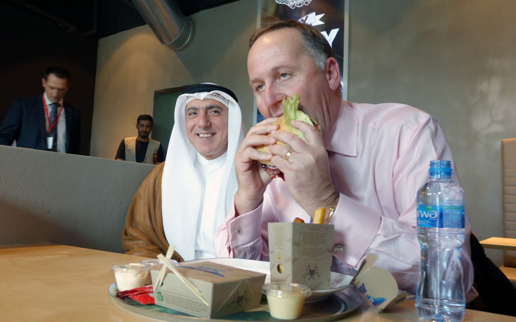Prime Minister John Key samples a burger at BurgerKing in Kuwait.