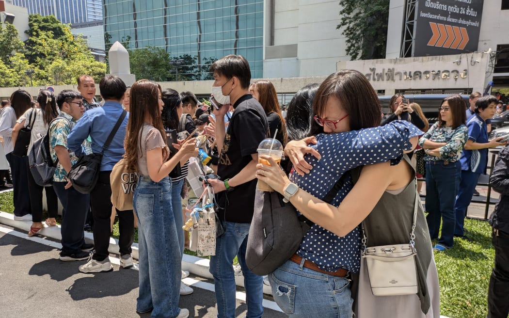 People stand outside an office building in Bangkok on March 28, 2025 after an earthquake. A powerful 7.7 magnitude earthquake hit central Myanmar on March 28, with tremors felt south into Thailand, with residents in the capital Bangkok runing into the streets as buildings shook. (Photo by Candida NG / AFP)