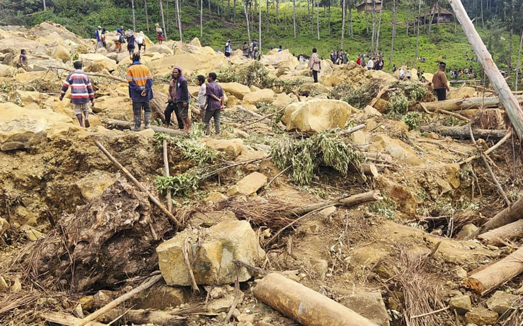 In this image provided by the International Organization for Migration, villagers search for bodies amid the rubble of a landslide in the village of Yambali in the highlands of Papua New Guinea, Monday, May 27, 2024. (Mohamud Omer/IOM via AP)