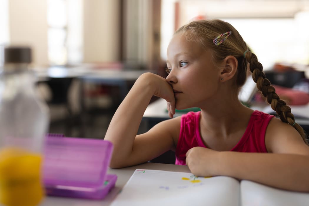Child inside classroom, thinking, day dreaming.