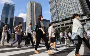 People wearing face masks are seen during commuting hour under a refreshing clear blue sky in front of Tokyo Station in Chiyoda Ward, Tokyo.