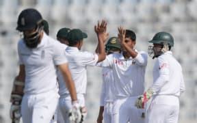 Bangladesh's Mehedi Hasan receives high fives from teammates after taking the wicket of England's Moeen Ali