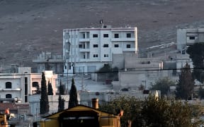 An Islamic State flag flutters on the roof of a building inside the Syrian town of Kobane. Another larger flag was planted on a hill.