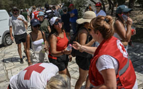 Hellenic Red Cross workers distribute bottles of water to visitors outside the Acropolis in Athens on 13 July, 2023, as Greece hits high temperatures.