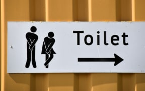 Toilet sign with two figures desperate to go.