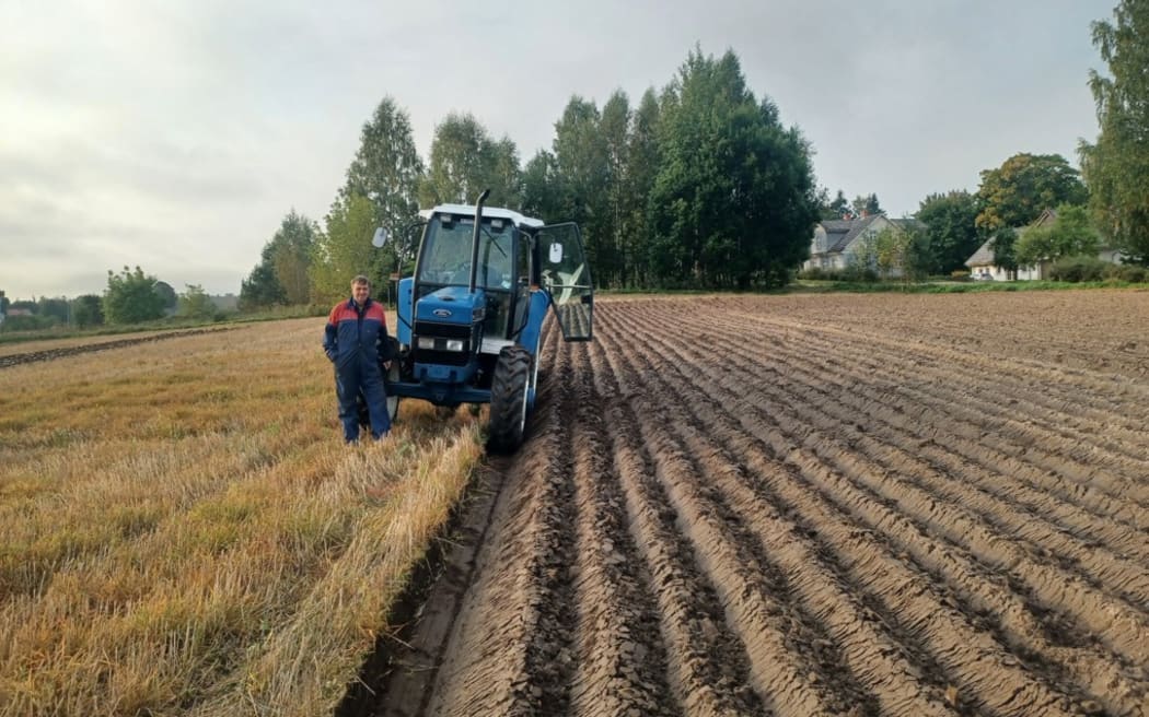 Bob Mehrtens stands next to his tractor and a freshly ploughed field.