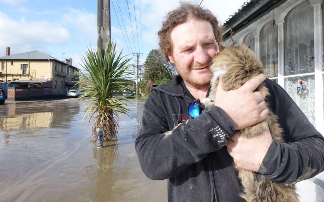 Aaron Fitton and his cat Iggy. Aaron's Waitotara house is knee high deep in water.
