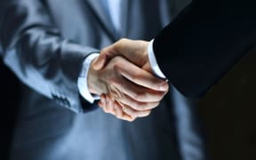 Two men in suits shake hands - close-up (file)