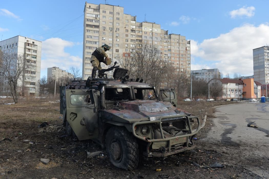 A Ukrainian Territorial Defence fighter examines a destroyed Russian infantry mobility vehicle GAZ Tigr after fighting in Kharkiv. Ukrainian forces secured full control of Ukraine's second biggest city on 27 February, 2022, following street fighting with Russian troops, the local governor said.