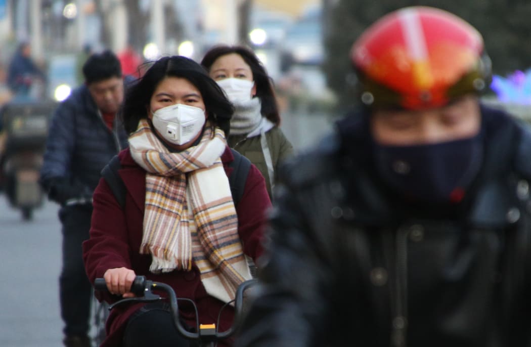 People wearing masks ride bycicles in Beijing, China on Jan. 21, 2020. Wuhan city announced that another patient had died due to the mysterious SARS-like virus on the previous day.