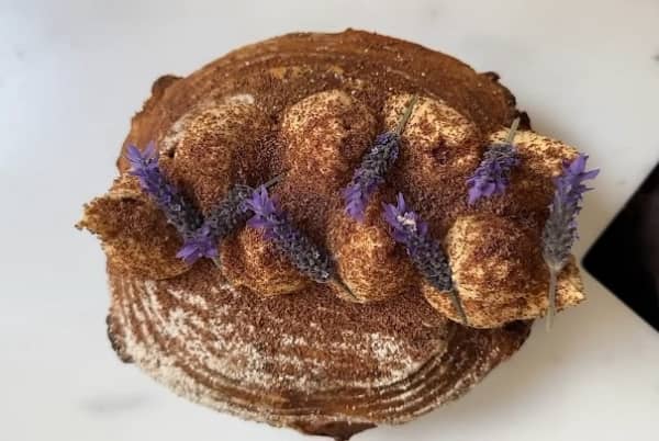 A brown loaf of bread with a creamy topping and grated chocolate.