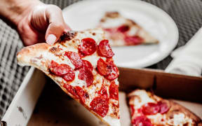 a person's hand holding a slice of pizza