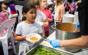 Children at Arakura School line up for free lunch