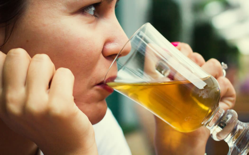 A woman drinks a glass of beer at a restaurant (file)