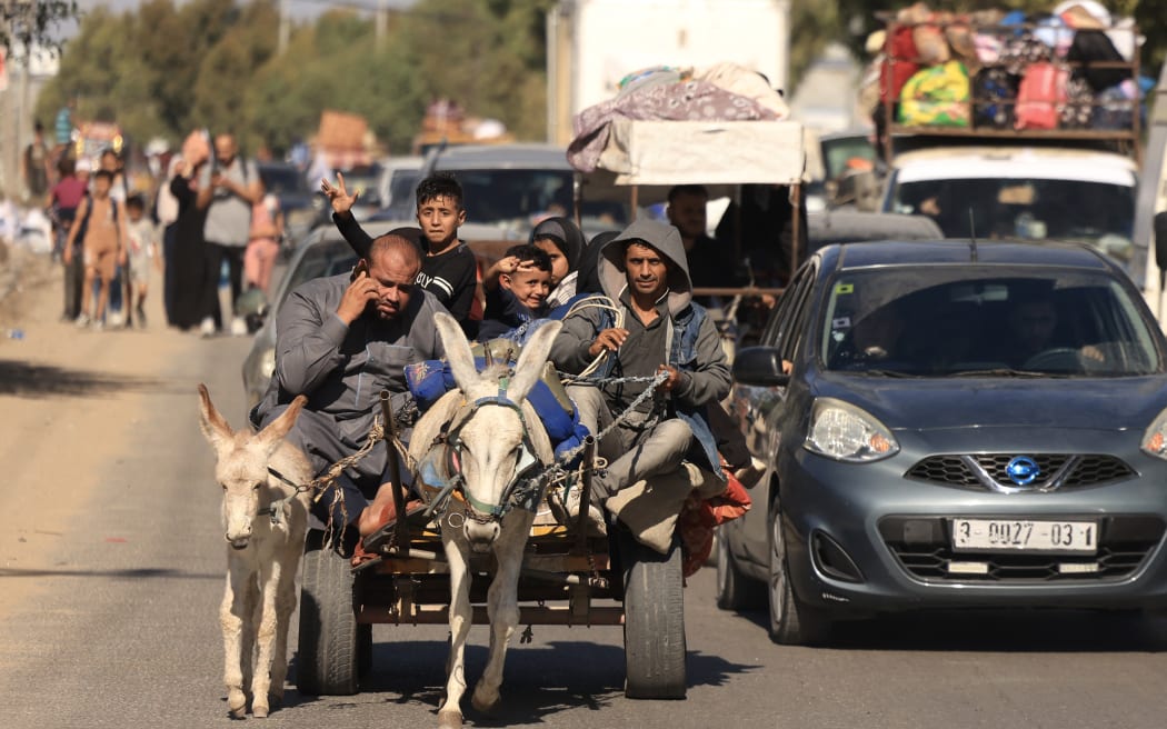 Riding a donkey drawn cart as family along with hundreds of other Palestinian carrying their belongings flee following the Israeli army's warning to leave their homes and move south before an expected ground offensive, in Gaza City on October 13, 2023. (Photo by MAHMUD HAMS / AFP)