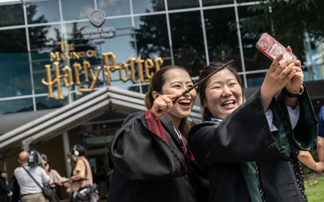 People wearing costumes pose for photographs in front of the entrance of the theme park "Warner Bros. Studio Tour Tokyo - The Making of Harry Potter" in Tokyo on June 16, 2023. (Photo by Yuichi YAMAZAKI / AFP)