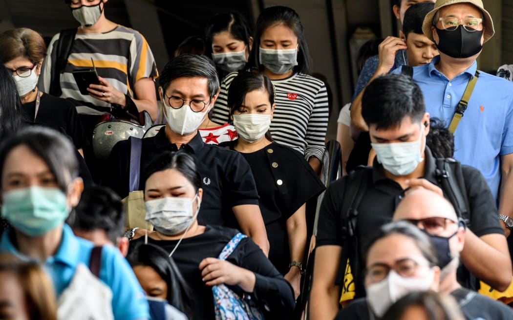 People wearing protective facemasks leave the city commuter train station in Bangkok.