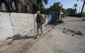 A member of the Iraqi security forces inspects the damage outside the Zawraa park in Baghdad on November 18, 2020, after rockets slammed into the Iraqi capital.