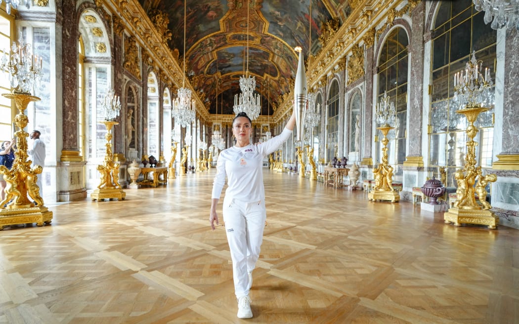 This handout photograph taken and released by The Paris 2024 press services on July 23, 2024, shows Mexican American actress Salma Hayek as she walks with the Olympic Torch as part of the 2024 Paris Olympic Games Torch Relay in The Hall of Mirrors (Galerie des Glaces) at Chateau de Versailles, west of Paris. (Photo by Laurent Vu / Paris 2024 / AFP) / RESTRICTED TO EDITORIAL USE - MANDATORY CREDIT "AFP PHOTO/PARIS 2024/LAURENT VU " - NO MARKETING NO ADVERTISING CAMPAIGNS - DISTRIBUTED AS A SERVICE TO CLIENTS