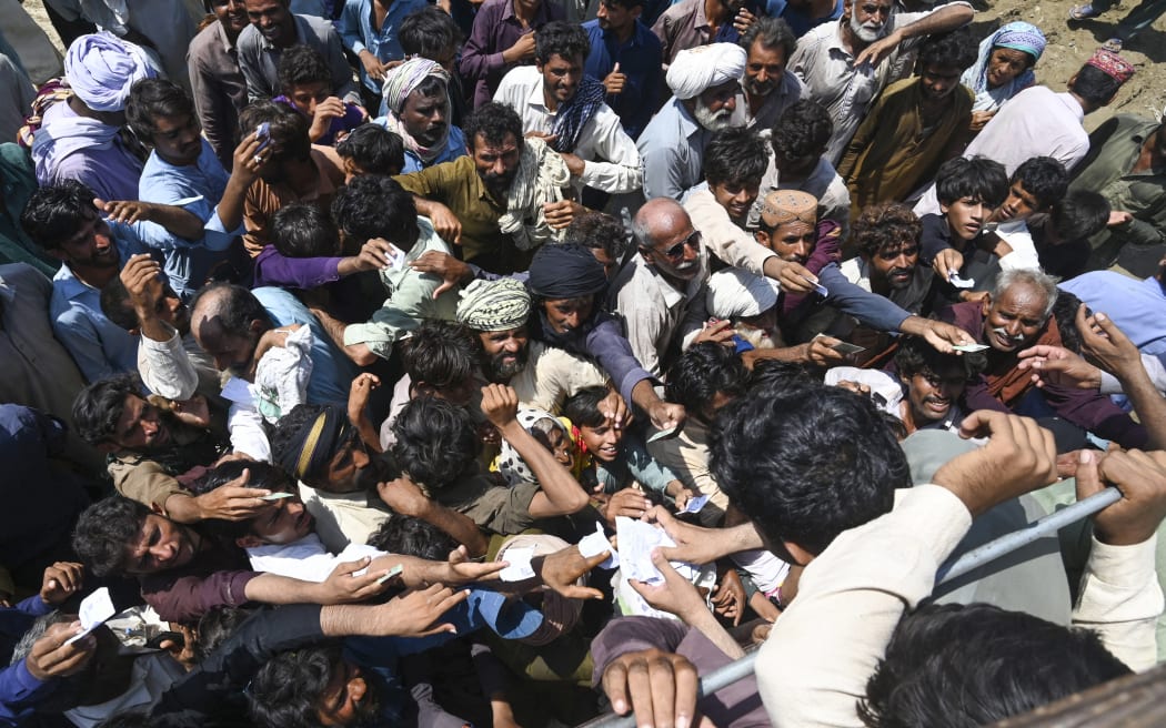 Flood-affected people scuffle to get relief food packets in Fazilpur, Rajanpur district of Punjab province on 3 September, 2022.