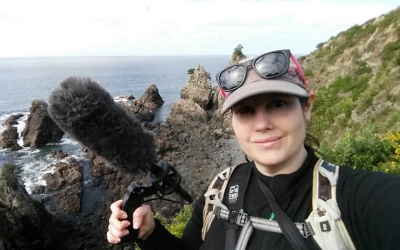 Michelle Roper on bird recording field work on an offshore island. She is holding a microphone.