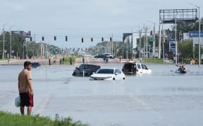 A young man looks on as cars are flooded in the water as the streets of the Southeast Seminole Heights section of Tampa due to Hurricane Milton on October 10, 2024 in Florida. Hurricane Milton tore a coast-to-coast path of destruction across the US state of Florida, whipping up a spate of deadly tornadoes that left at least four people dead, but avoiding the catastrophic devastation officials had feared. (Photo by Bryan R. SMITH / AFP)