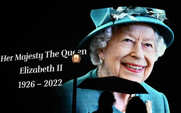 Members of the public stop in the rain to study a huge picture of Britain's Queen Elizabeth II displayed at Piccadilly Circus in central London on September 9, 2022, after the announcement of her death.