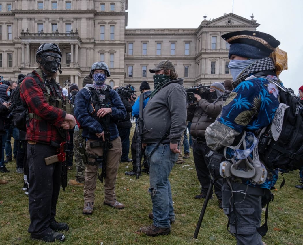 Members of the Michigan Boogaloo Bois an anti-government group stand with their long guns near the Capitol Building in Lansing, Michigan.