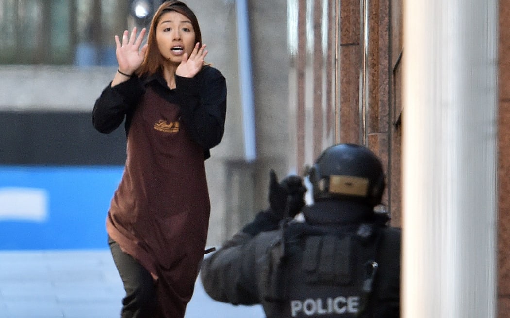 A young woman flees after being held hostage in a central Sydney cafe.