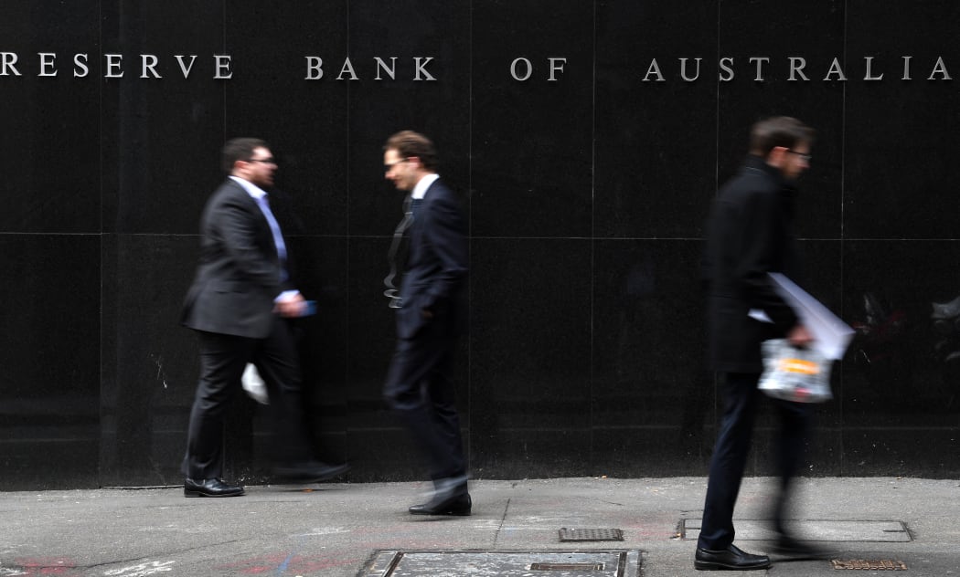 Office employees walk in front of the Reserve Bank of Australia in Sydney on September 4, 2018. - Weak inflation, sluggish wage growth and high levels of household debt saw Australia's central bank keep interest rates on hold at a record low on September 4. (Photo by Saeed KHAN / AFP)