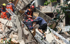 This photo taken by Taiwan's Central News Agency (CNA) on April 3, 2024 shows emergency workers assisting a survivor after he was rescued from a damaged building in New Taipei City, after a major earthquake hit Taiwan's east. A major 7.4-magnitude earthquake hit Taiwan's east on the morning of April 3, prompting tsunami warnings for the self-ruled island as well as parts of southern Japan and the Philippines. (Photo by CNA / AFP) / Taiwan OUT - China OUT - Macau OUT / Hong Kong OUT RESTRICTED TO EDITORIAL USE