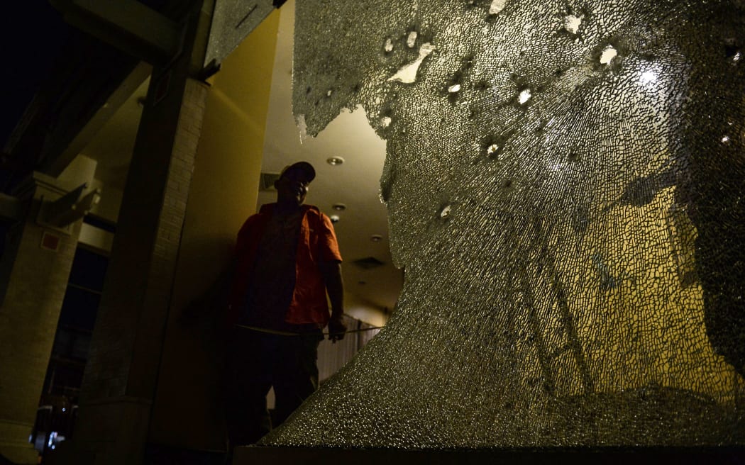 A labourer inspects the damage done to the glass windows of a Starbucks branch next to the site of a bomb attack in Hua Hin.