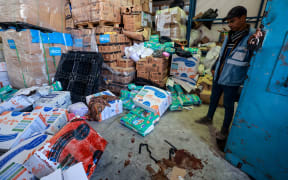 A UN (United Nations) staff stands near a pool of blood at an UNRWA warehouse and distribution centre in Rafah, in the southern Gaza Strip, following an Israeli strike on March 13, 2024, amid continuing battles between Israel and the Palestinian militant group Hamas. The UN agency for Palestinian refugees said one of its warehouses in war-ravaged Gaza was hit on March 13, amid mounting efforts to bring food to the besieged Palestinian territory. (Photo by MOHAMMED ABED / AFP)