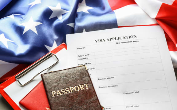Passports, American flag and visa application form on table. Immigration to USA.