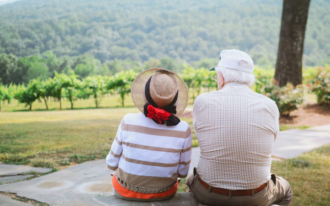 An elderly couple sitting outdoors in nature.