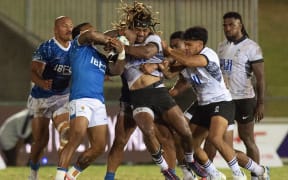 Fiji's Selestino Ravutaumada (C) tries to avoid a tackle from Samoa's Theo McFarland (L) during the World Rugby Pacific Challenge 2024 match between Fiji and Samoa at the HFC Bank Stadium in Suva on August 23, 2024. (Photo by LEON LORD / AFP)