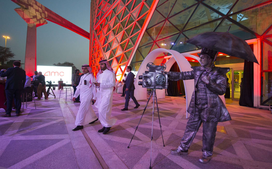 A handout picture provided by the Saudi Royal Palace on 18 April shows a mime actor standing behind a model vintage cinema camera at the entrance of the AMC cinema in the capital Riyadh.