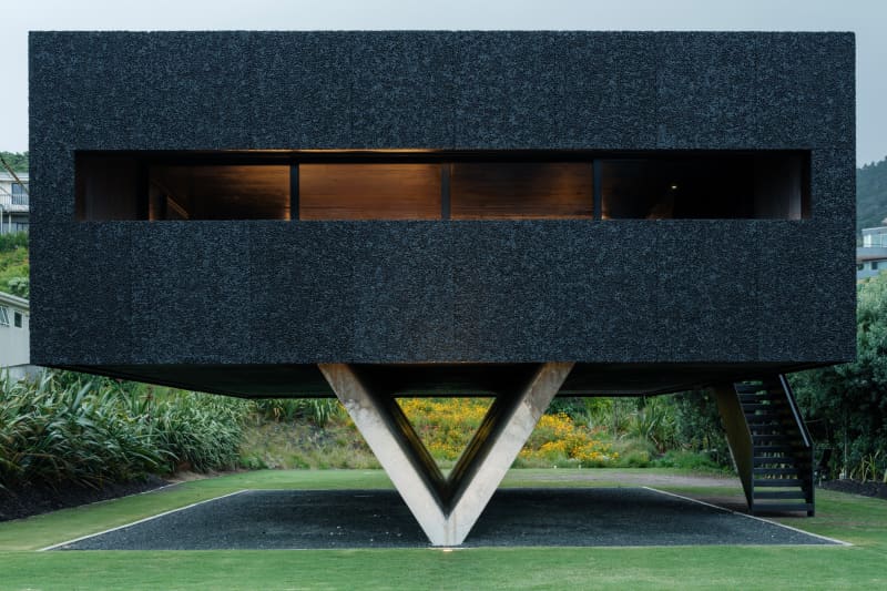 An image of a house installed on concrete V-shaped stilts in Piha.