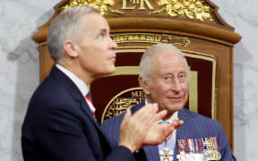 Canada's  Prime Minister Mark Carney claps after Britain's King Charles III delivered the Speech from the Throne during the opening the first session of the 45th Parliament of Canada at the Senate of Canada in Ottawa on May 27, 2025. Britain's King Charles III is heading to Canada for a brief but "impactful" visit, at a time when President Donald Trump is floating the idea of making his northern neighbour the 51st US state. The 76-year-old monarch, who is also Canada's head of state as part of the Commonwealth, has never publicly commented on the ambitions of the US president, a noted admirer of the royal family. (Photo by Blair Gable / POOL / AFP)