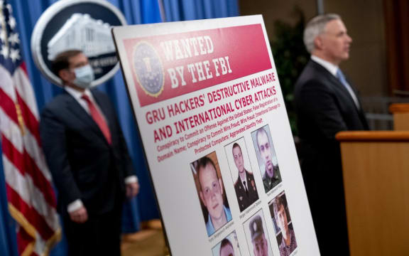 A poster showing six wanted Russian military intelligence officers is displayed as US Attorney for the Western District of Pennsylvania Scott Brady speaks at a news conference at the Department of Justice.