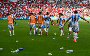 Argentina's forward #17 Giuliano Simeone (2ndR) looks on as water bottles thrown by Morroco's fans litter the pitch after Argentina scored their second goal, which was cancelled after a two-hour interruption, in the men's group B football match between Argentina and Morocco during the Paris 2024 Olympic Games at the Geoffroy-Guichard Stadium in Saint-Etienne on July 24, 2024. (Photo by Arnaud FINISTRE / AFP)