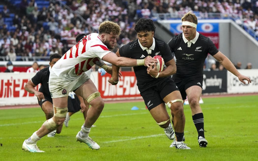 Wallace Sititi of the All Blacks (R) right fends off Japan's Warner Dearns.