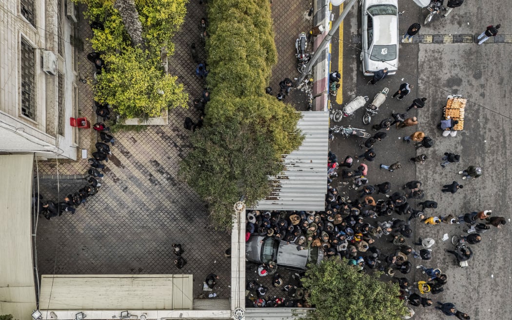Men wait outside a transitional government centre to hand over small arms and security registration for former soldiers, police members, and civilians in Damascus on 24 December, 2024.