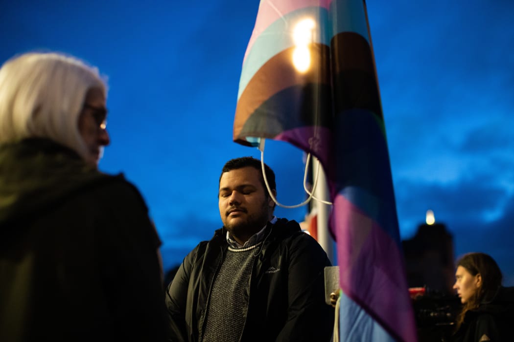Petazae Thoms closes his eyes for a moment's reflection before helping raise an LGBTQI flag in commemoration of the 35th anniversary of passing of the Homosexual Law Reform Act.
