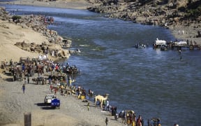 Ethiopian refugees who fled the fighting in the Tigray region gather on the banks of a border river with Sudan, in the Hamdayit area of Sudan's eastern Kassala state.