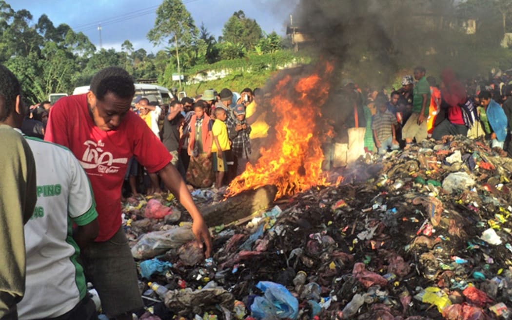 A photo taken on February 6, 2013 shows a crowd watching as a young mother accused of sorcery, is stripped naked, reportedly tortured with a branding iron, tied up, splashed with fuel and set alight