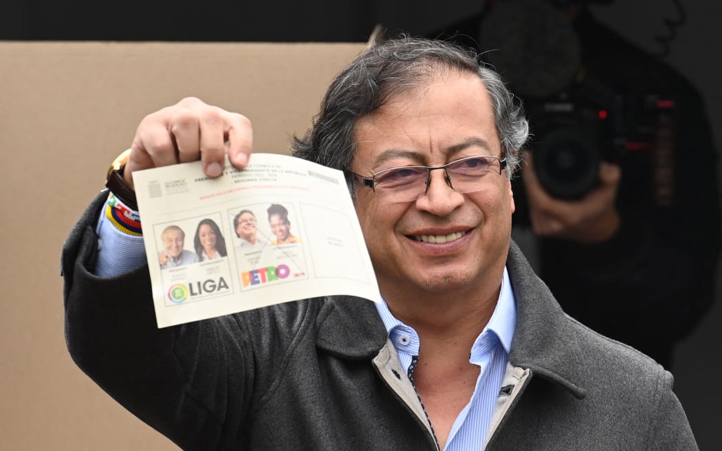 Gustavo Petro holds up his ballot paper as he votes during the presidential runoff election in Bogota, on 19 June, 2022.