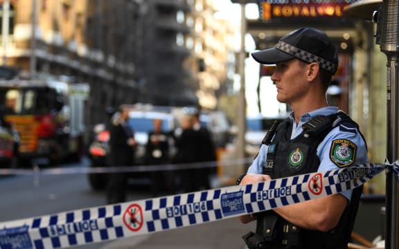 A policeman stands by a roped off crime scene after a man stabbed a woman and attempted to stab others in central Sydney.